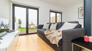 Una sala de estar moderna con un sofá gris, un televisor de pantalla plana y piso de madera.