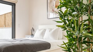 Un dormitorio moderno con cama, cabecero blanco y una ventana grande.
