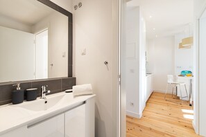 Un bagno moderno con uno specchio grande, un lavandino bianco e uno schienale piastrellato scuro.