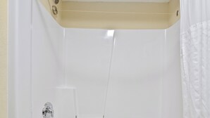Una bañera blanca con cabezal de ducha, toallero y cortina de baño.