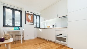 A modern kitchen with white cabinets, a built-in oven, and a window overlooking the city. - Belem Design 09 by Homing (Lisbon)