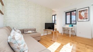 A modern living room with a sofa, a TV, a small table, and a window. - Belem Design 09 by Homing (Lisbon)