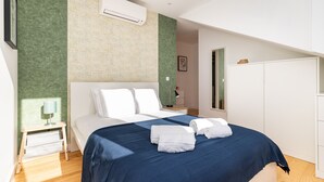 A modern bedroom with a large bed, a nightstand, a bedside lamp, and a wardrobe. - Belem Design 09 by Homing (Lisbon)