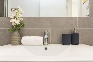 A bathroom sink with a vase of flowers, a towel, and two soap dispensers. - Belem Design 13 by Homing (Lisbon)