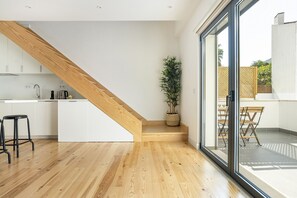 Una cucina moderna con pavimento in legno, mobili bianchi e una scala in legno.