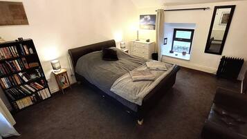 Quarto com cama, estante, cômoda, janela com vista e radiador.