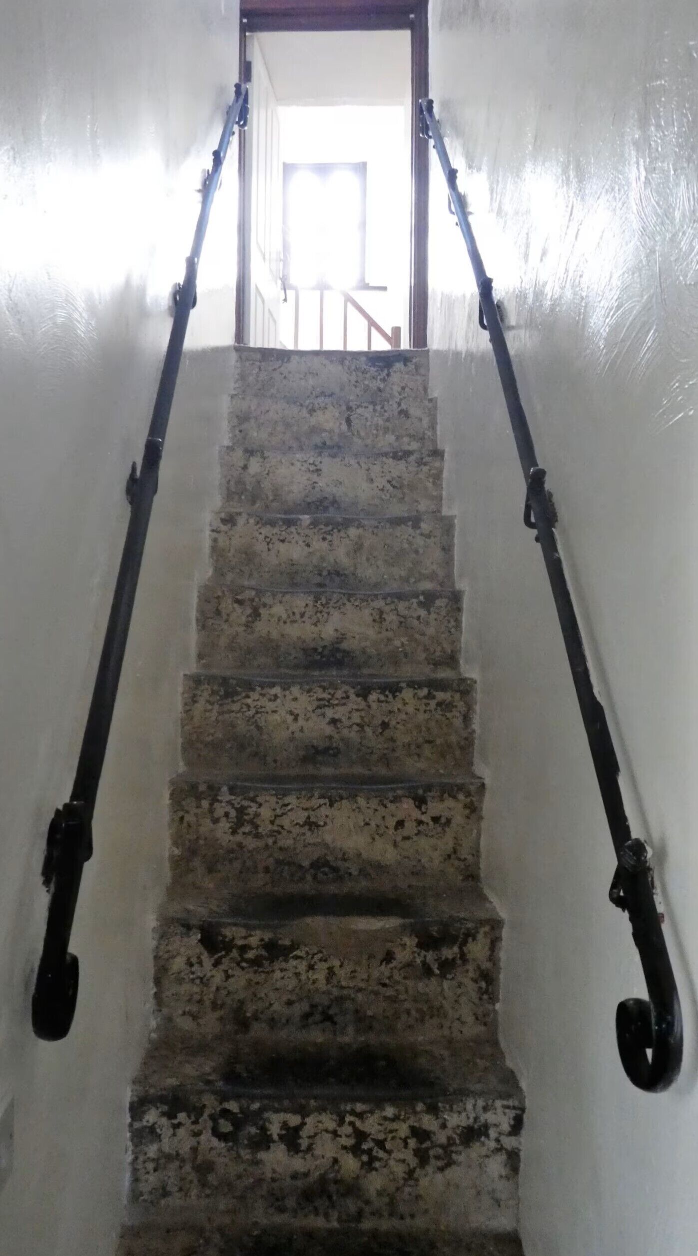 A staircase with a handrail, leading to a doorway at the top.