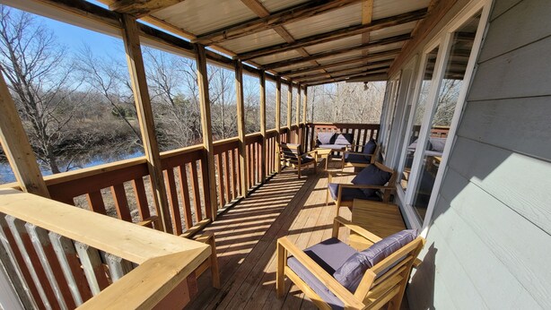 Une terrasse extérieure couverte, aménagée avec du mobilier en bois et offrant une vue sur le paysage environnant.
