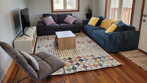 Un salon avec un canapé, une table basse, un téléviseur et une plante en pot.