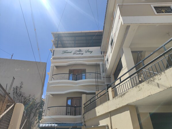 Un edificio de varios pisos con balcones y un letrero que dice "Travel Residency Stay".