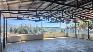 A spacious covered terrace with a clear view of a hilly landscape. - Travel & Stay (Ootacamund)