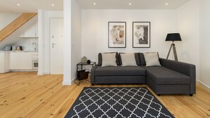 A modern living room with a grey sectional sofa, a black and white patterned rug, and two framed artworks on the wall. - Belem Design 15 by Homing (Lisbon)