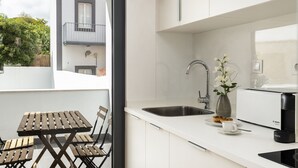 A modern kitchen with a white countertop, a Bosch coffee maker, a sink, and a dining area with a wooden table and chairs. - Belem Design 14 by Homing (Lisbon)