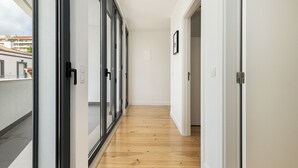 A narrow hallway with wooden flooring, glass doors, and white walls. - Belem Design 14 by Homing (Lisbon)