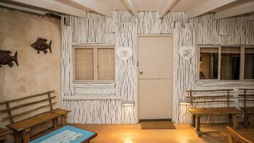 Una habitación con bancos de madera, una puerta con un letrero en forma de corazón y una ventana con persianas.