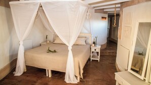 A bedroom with a four-poster bed, bedside tables, and a mirror.