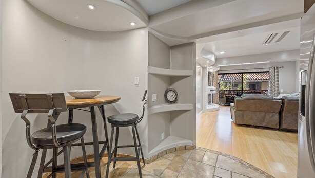 Una cocina moderna con comedor, que incluye un taburete de bar, una mesa de madera y un bol.
