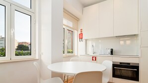 Een moderne keuken met witte kasten, een inbouwoven en een ronde tafel met stoelen.