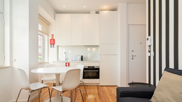 Een moderne keuken met witte kasten, een ronde eettafel met stoelen en een inbouwoven.