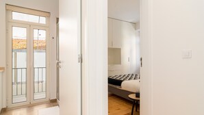 Una habitación con una cama, una mesita y una puerta que da a un balcón.