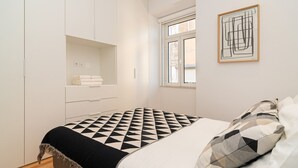 Un dormitorio con cama, armario, ventana y una obra de arte enmarcada en la pared.