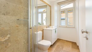 Une salle de bain avec une douche à parois de verre, des toilettes, un lavabo et une fenêtre donnant sur un beau paysage.
