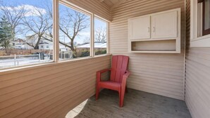 Et hjørneværelse med en rød stol, store vinduer og et træloft.
