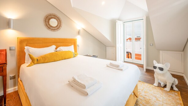 A hotel room with a large bed, a wooden headboard, and a small dog statue. - Bairro Alto Prime Duplex by Homing (Lisbon)