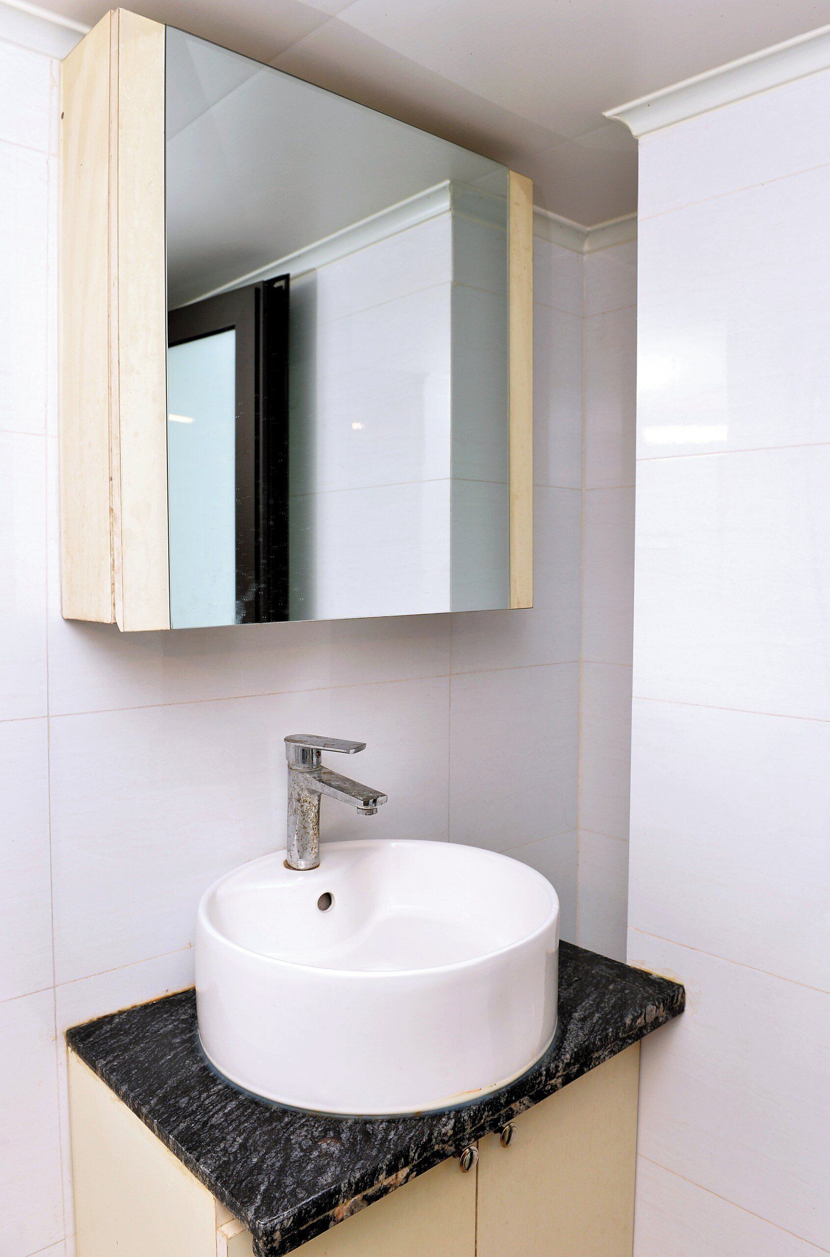 Un baño con un lavamanos blanco, un espejo y una encimera negra.