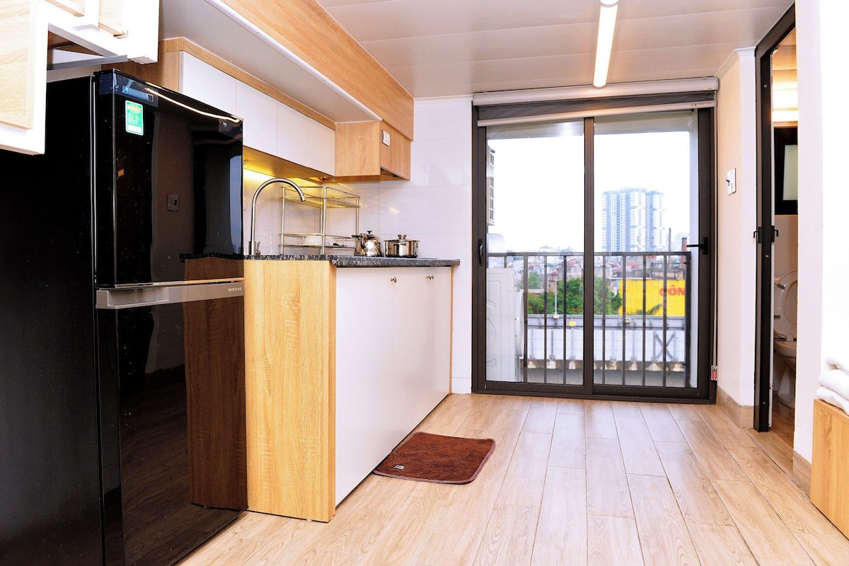 Eine moderne Küche mit einem schwarzen Kühlschrank, Holzschränken und einer Glastür, die auf einen Balkon führt.