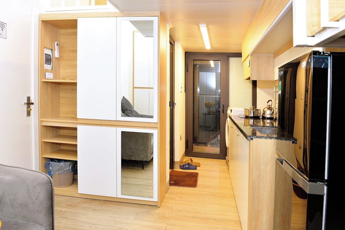 Eine kleine Küche mit Holzschränken, einem schwarzen Kühlschrank und einer Arbeitsplatte.