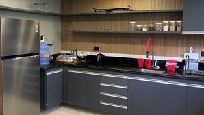 A modern kitchen with a stainless steel refrigerator, a water dispenser, and a gas stove. There are cabinets with drawers and a countertop with various kitchen items.