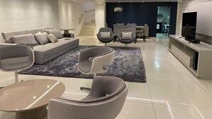 A modern living room with a sofa, chairs, a coffee table, a TV, and a staircase leading to another room.