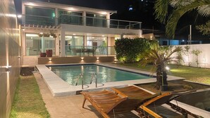 A modern house with a swimming pool, wooden deck, and outdoor furniture.