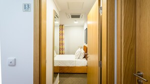 A hotel room with a bed, a wooden door, and a number sign on the wall.