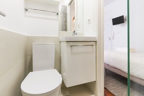 Et lille, kompakt badeværelse med toilet, håndvask og spejl.