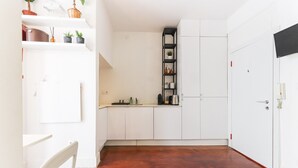 Eine kleine Küche mit weißen Schränken, Holzboden und einer Arbeitsplatte.