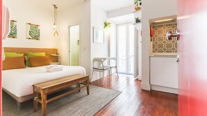 Ein Schlafzimmer mit Bett, Nachttisch, Bank und Blick auf den Balkon.