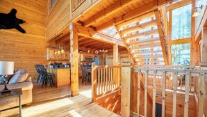 Ein Holzhäuschen-Innenraum mit Küche, Essbereich und einem Balkon mit Holzgeländer.