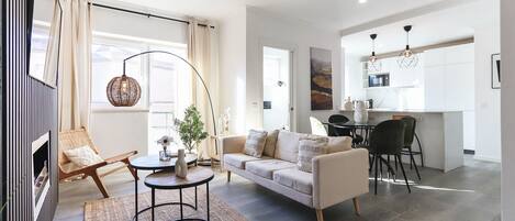 A modern living room with a sofa, coffee table, and a dining area with chairs.