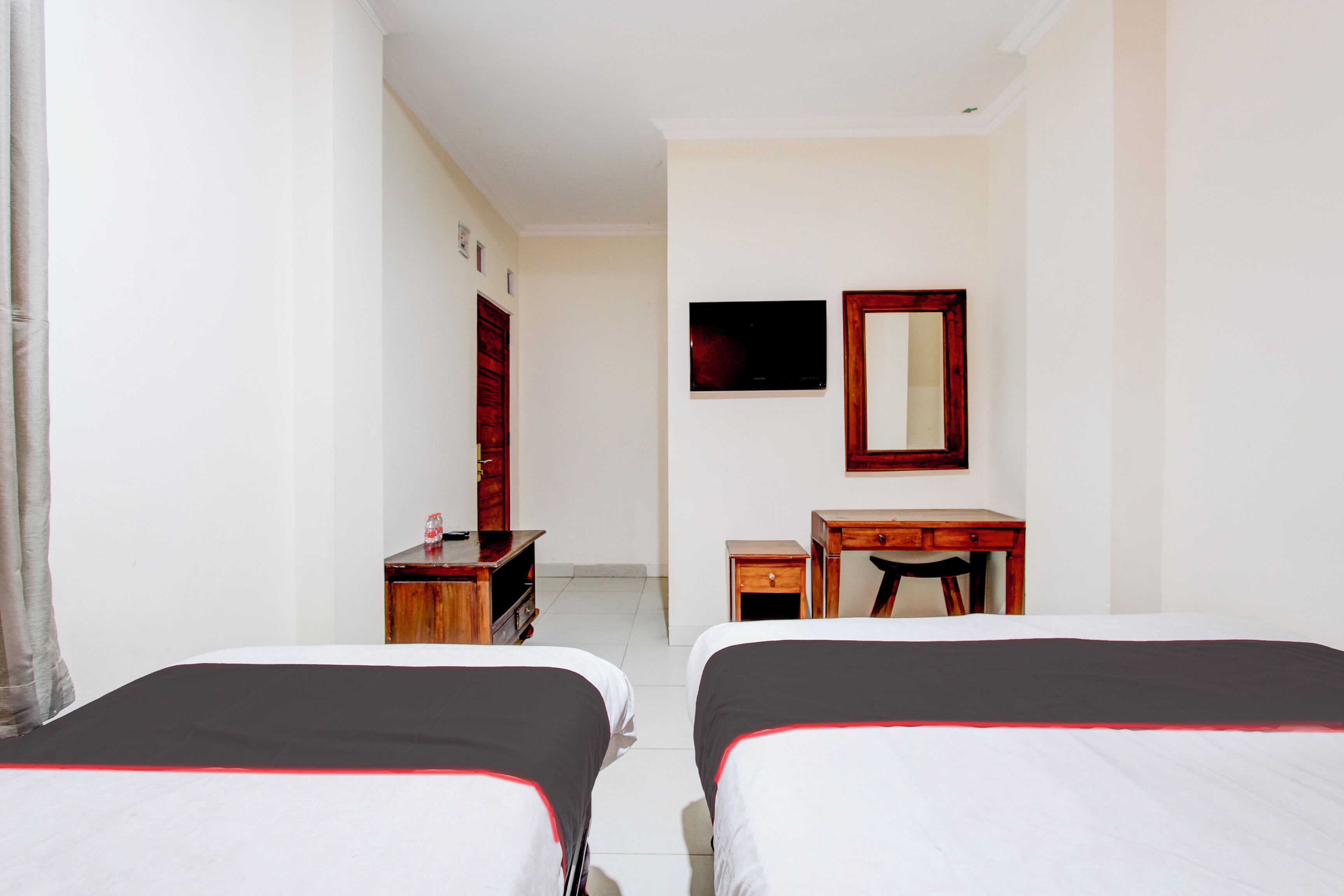 Une chambre d’hôtel avec deux lits, un bureau, une chaise, une télévision et un miroir.