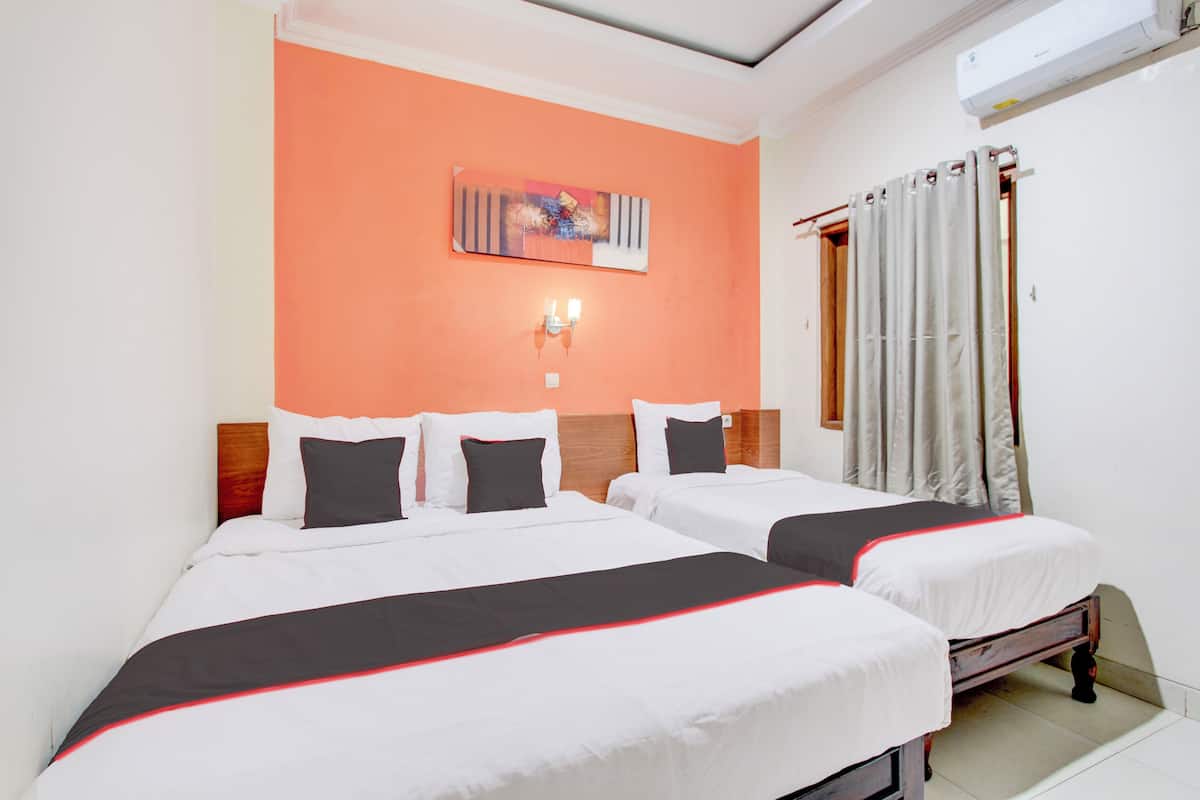 Habitación de hotel con dos camas, un cuadro en la pared, un ventilador de techo y una ventana con cortinas.
