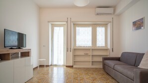 A living room with a sofa, TV, and a window with curtains. - Roman Style II near San Pietro - 10 minutes from Vatican and St Peter's Basilica (Roma)