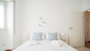 A neatly made bed with white linens, two pillows with a blue pattern, and a wall with inspirational text. - Roman Style II near San Pietro - 10 minutes from Vatican and St Peter's Basilica (Roma)