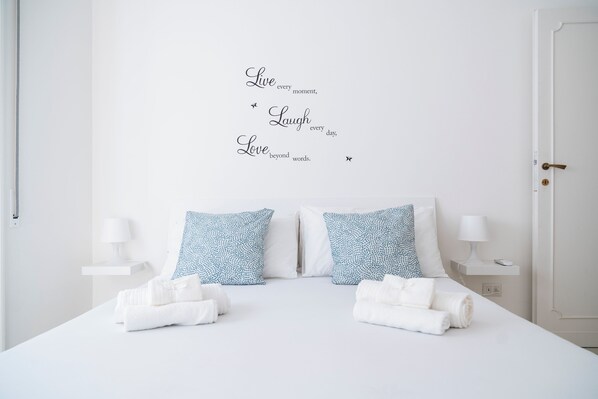 A neatly made bed with two pillows, a bedside table with a lamp, and a wall with inspirational text. - Roman Style II near San Pietro - 10 minutes from Vatican and St Peter's Basilica (Roma)