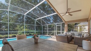A covered outdoor area with a pool, wicker furniture, and a ceiling fan. - Private Pool Villa Near Major Theme Parks – Quiet Gated Golf Community (Haines City)