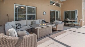 An outdoor patio area with a sofa, chairs, a table, and a fire feature. - Private Pool Villa Near Major Theme Parks – Quiet Gated Golf Community (Haines City)