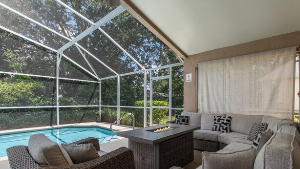 A covered outdoor area with a pool, wicker furniture, and a fire feature. - Private Pool Villa Near Major Theme Parks – Quiet Gated Golf Community (Haines City)