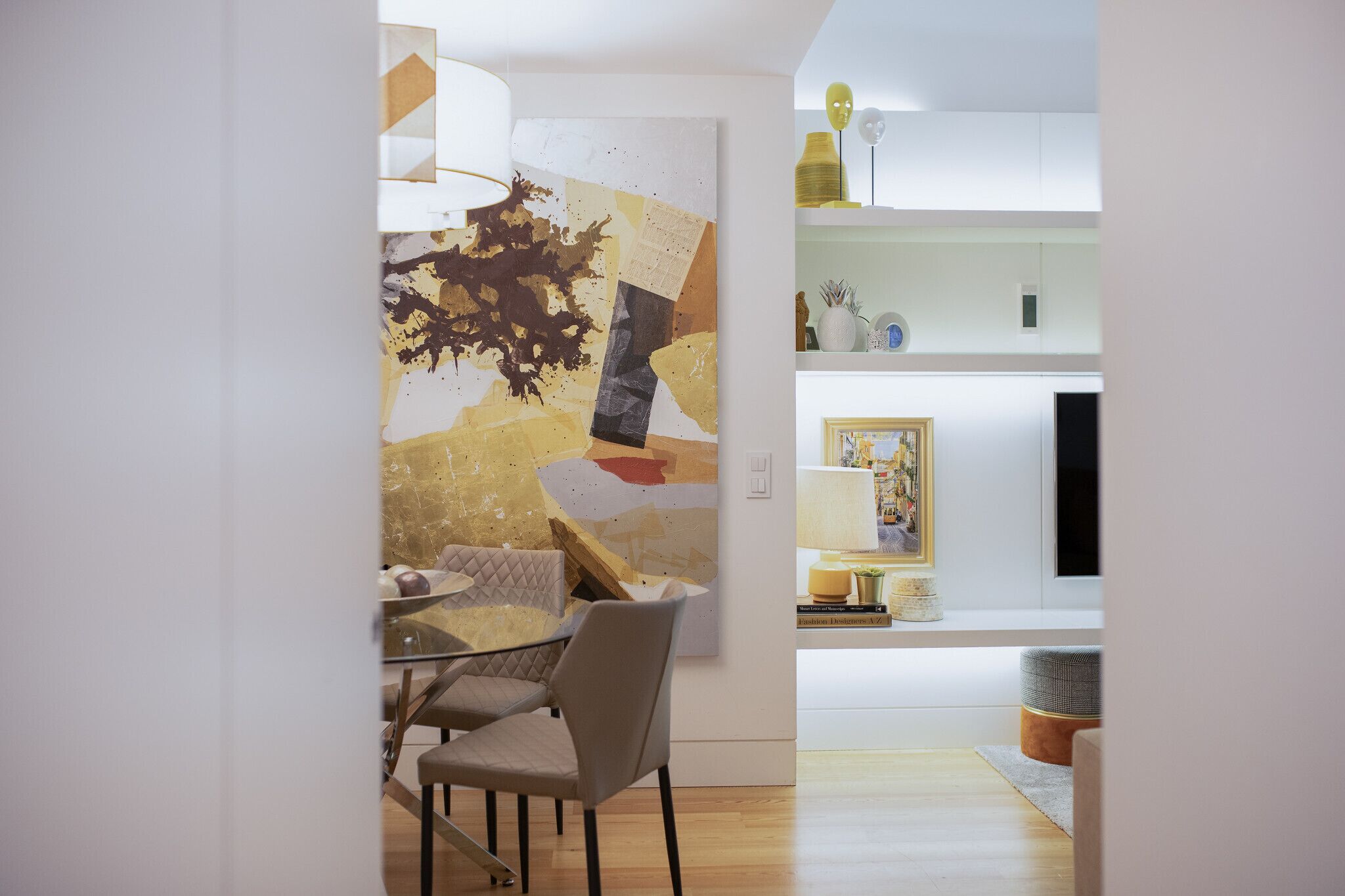 Un'area pranzo moderna con tavolo e sedie, un grande quadro astratto appeso alla parete e un angolo cottura sullo sfondo.