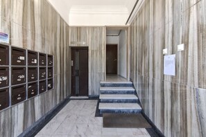 Stunning hallway with marble floors and steps, featuring a series of mailboxes and a door at the end.